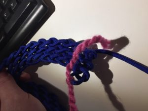 Some woven paracord with a pink piece of yarn tied to it
